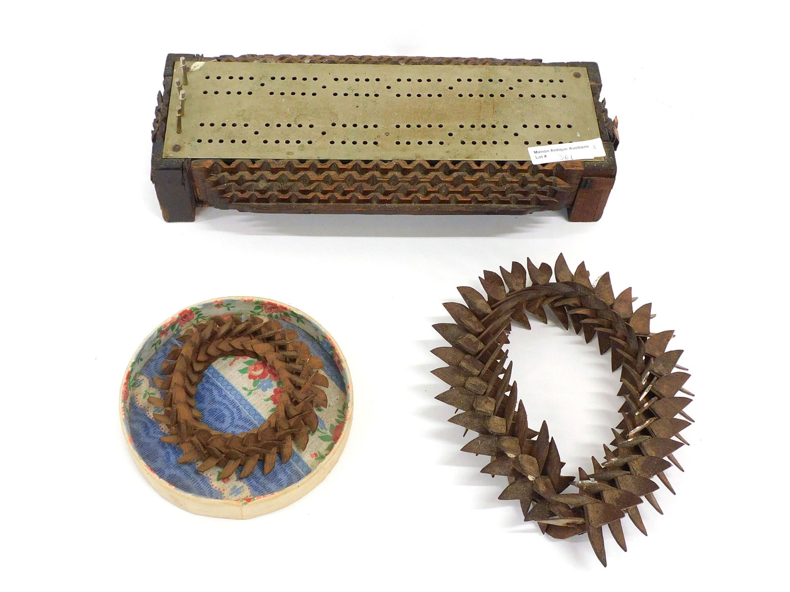 (3) Tramp Art Items: Late 19th C. To include: (A) Cribbage board. 2 1/4" high x 10 3/4" wide x 5" deep. Comes with four pins. (B) Small wreath. 1" high x 4" diameter. (C) Oval frame with a wood back. 1 1/2" high x 7" long