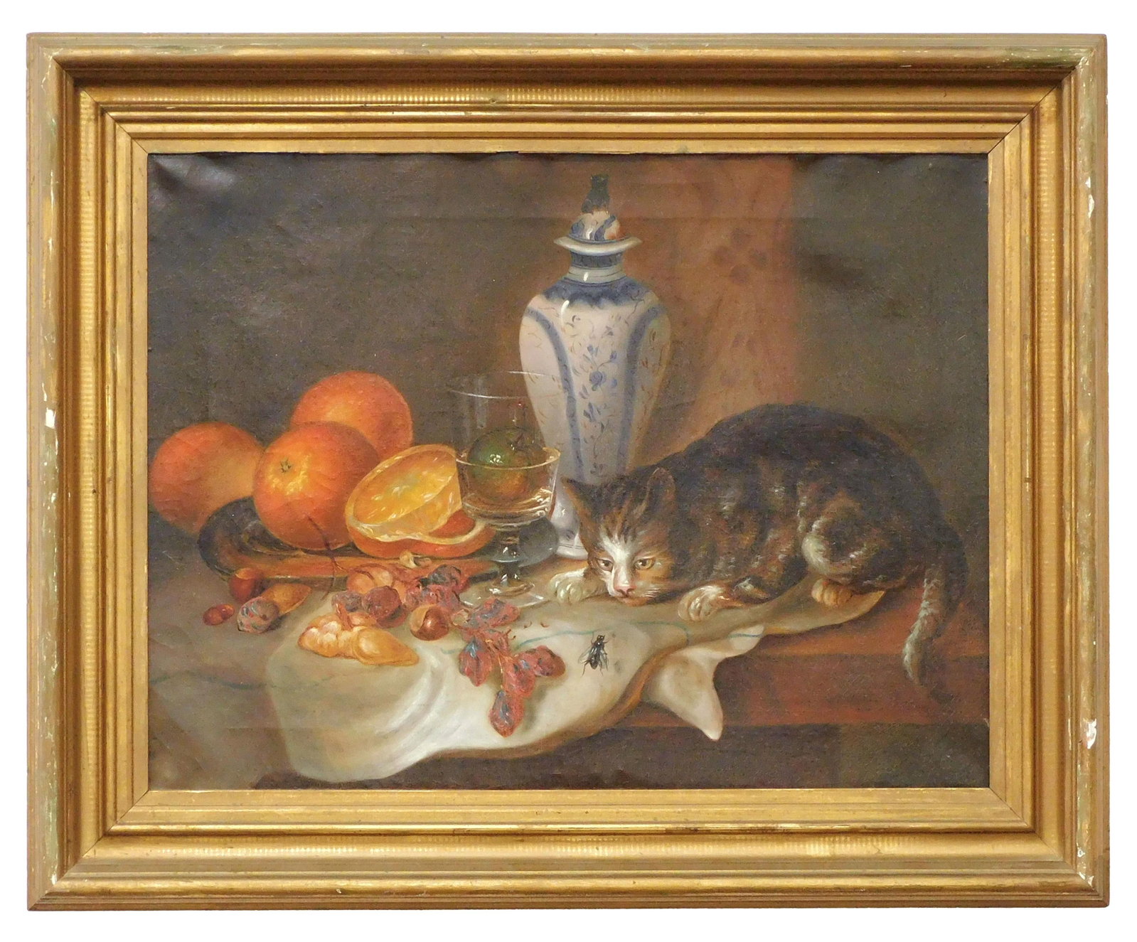 Still Life Painting: Late 19th C. Oil on canvas. Unsigned. Depicts oranges, nuts, a porcelain vase and a tiger cat poised to attack a bee. Sight size 15 1/2" high x 20 1/2" wide. In a period carved and gilded frame measur