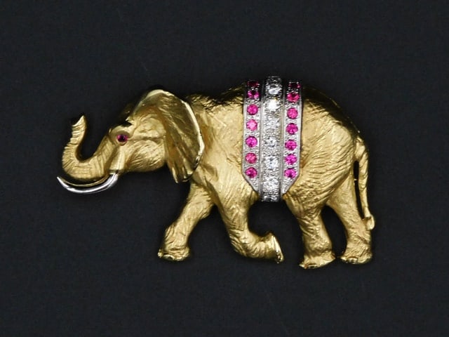 Gold Elephant Pin with Diamonds and Rubies: 20th C. Tests 14kt. Signed. Yellow gold body with white gold tusk, ruby eye and a diamond and ruby saddle. 1 1/4" high x 2 1/4" wide. 13.9 dwt. Please note this lot must be paid for by cash, wire tran