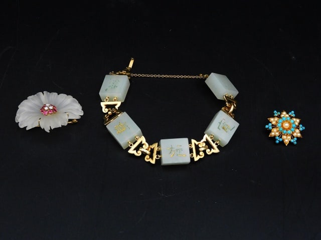 (3) Pieces Gold Jewelry: 20th C. All test 14kt. To include: (A) Engraved white jade bracelet with Chinese characters. 8" long. (B) Yellow gold, diamond, ruby and rock crystal carved floral pin. 1 3/4" diameter. (C) Pin pendan