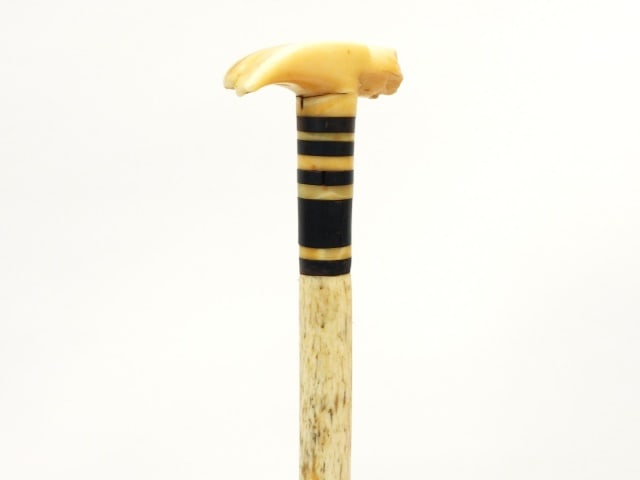 Scrimshaw Walking Stick: 19th C. Hammer form. Whale's tooth top. Ebony and whale's tooth disk inlay. Brass tip. 35 1/4" long. Along with a copy of Scrimshaw and Scrimshanders by E. Norman Flayderman, 1972. 10 1/2" high x 8 1/