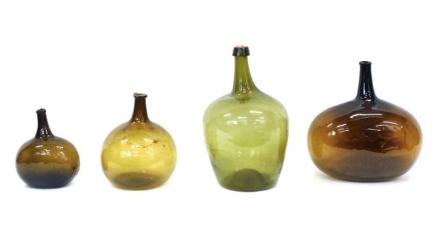 (5) Blown Demijohn Bottles: 18th/19th C. Various shades of green. Ranging in size from 11" to 19 1/2" high x 8 1/2" to 15" wide. Provenance: From the estate of Rodney Hilton Brown.