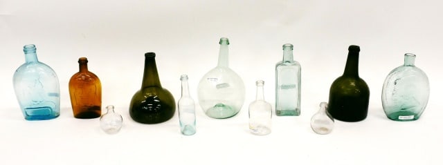 (11) Bottles and Flasks: 19th C. To include: (A) Amber double eagle. 7 1/2" high. (B) Dyottville glassworks Washington and General Taylor flask. 8" high. (C) Early blown green squat bottle. 8 1/4" high. (D) Blown green bottle
