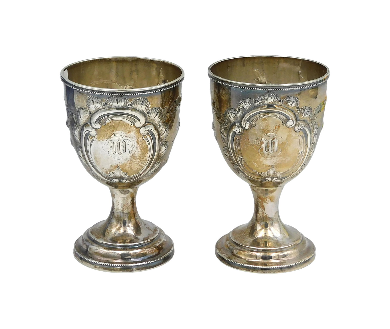 Pair of Coin Silver Goblets: 19th C. Lincoln and Foss, Boston. Raised floral design with central cartouche displaying a W monogram. 5" high. 8.69 total ozt. Provenance: From the estate of Alfred J. Walker, legendary art