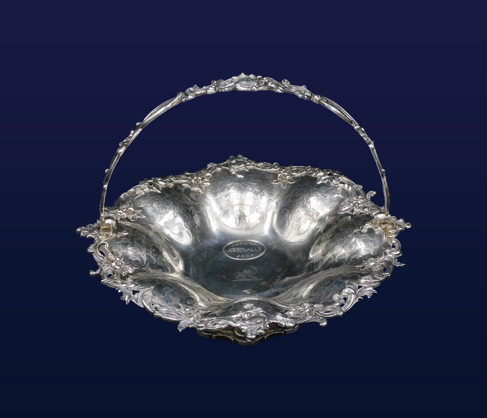 Sterling Silver Swing Handle Basket: 19th C. Edward & John Barnard, London. Open cutwork embossed floral border. Engraved scallop convex sides. Center engraved: London, Aspinall's 2000 which likely a modern addition. Also has an Aspinall