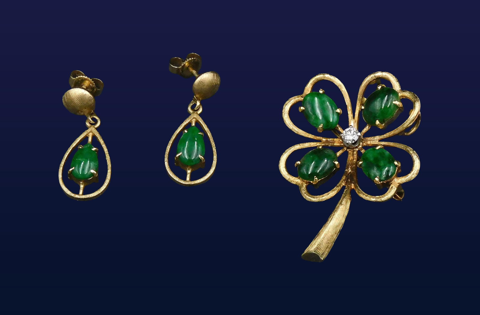 Brooch and Earrings Set: 14kt yellow gold and Maw Sit Sit jade. Brooch is in the form of a four leaf clover and has a small diamond at its center. Earrings are dangles and have 14kt backs. 6.4 dwt.One of the earrings' jade sh
