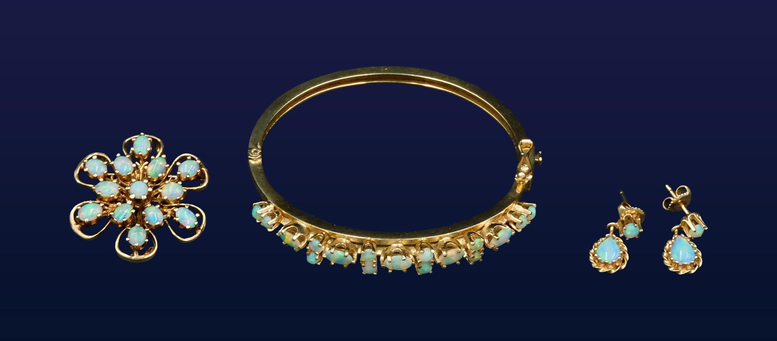 14kt Yellow Gold and Opal Jewelry Set: Consisting of a bracelet, brooch/pendant and a pair of earrings. Luminous and vibrant opals. 18.9 dwt. No missing stones. One stone on the brooch shows a chip. Please note this lot must be paid for by