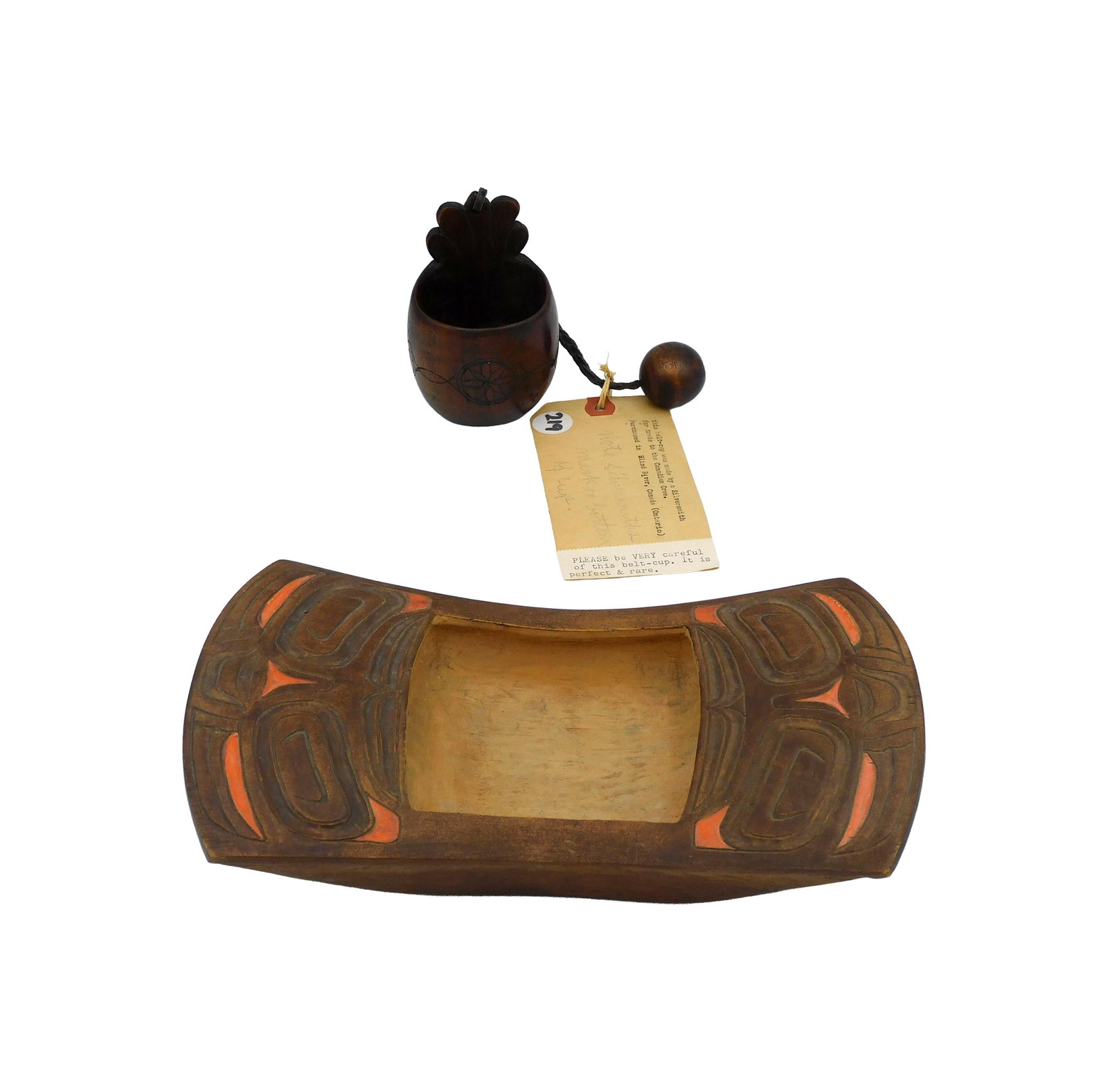 Northwest Coast Wood Bowl With Belt Cup: To include: (A) 20th C. Carved pine with Haida red pigment decoration. Marked "Harvey" on bottom. 10" long x 6" wide. (B) 19th C. Belt cup. Fruitwood. Carved with compass rose and scrolls. Leather str