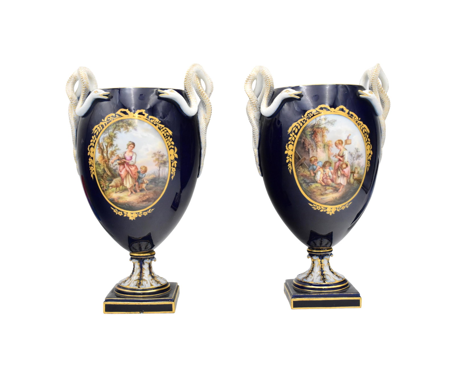 Pair of Meissen Porcelain Snake-Handled Urns: Late 19th/Early 20th C. Undersides marked. Cobalt blue ground, gilt decoration, and entwined serpent-form handles. The bodies show oval reserve panels painted with figural pastoral scenes, raised on f