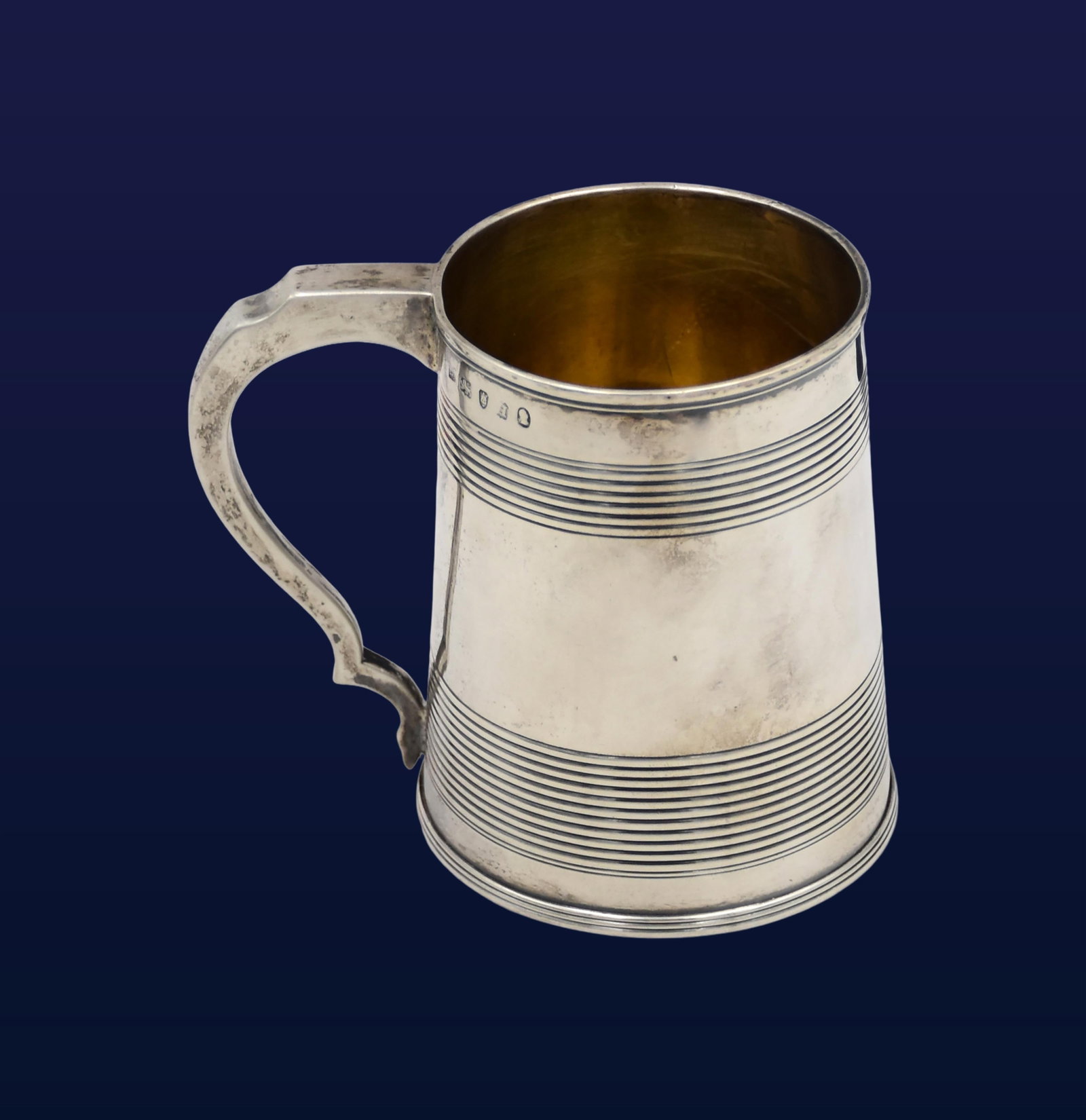 Georgian Sterling Silver Mug: Early 19th C. Reeded bands to upper and lower body. Shaped handle. Hallmarked near rim. 4 1/4" high x 5" wide x 3" diameter. 8.03 ozt.Condition consistent with age and use. IMPORTANT- Please note: