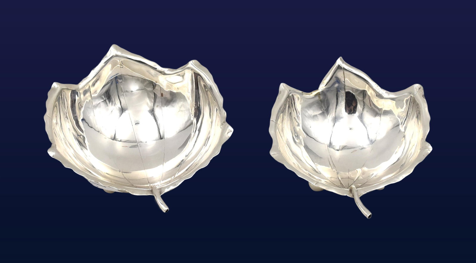(2) Sterling Silver Nesting Nut/Bonbon Dishes: 20th C. Leaf-form with stem handle and veined bowl. Resting on three spherical feet. Stamped sterling on bottom with an unknown maker. Larger dish: 1 3/4" high x 5 1/2" long from tip to end of stem.