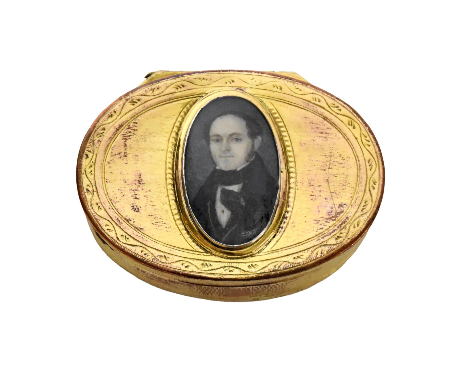 Snuff Box with Miniature Portrait: Ca. 1830. Portrait depicts a young man with his dog. Engraved floral design on bottom. Oval. 10kt gold laminate on copper. Two hallmarks. 3/4" high x 2 1/2" long x 2" deep. Provenance: Vanderbilt Fami