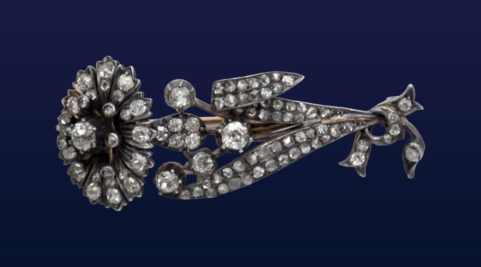 Diamond Set Brooch: Late 19th/Early 20th C. Modeled as a flower with a bold floral spray. Set in white metal on gold. Set with old mine cut and rose cut diamonds. 2" high x 7/8" wide. 11. 1 grams. Good condition.
