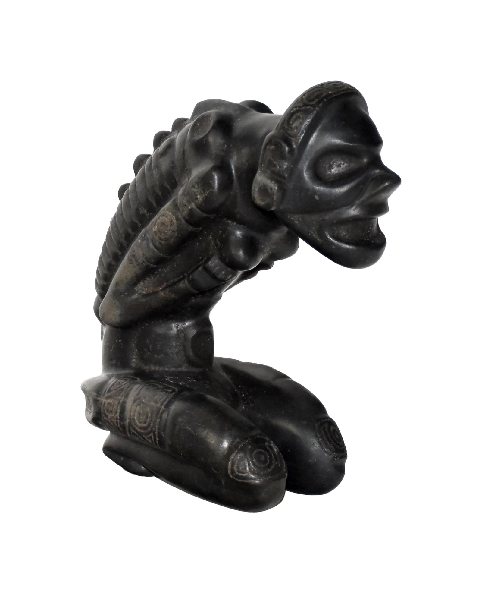 Taino Cacica Shaman in an Ecstatic Trance: Ca. 1200-1500 AD. Magnetite. 9 3/4" high x 4" wide x 9" deep. The figure is kneeling, grasping her breasts, accentuating her stress. The Cacica's tormented face and skeletal form suggest the process