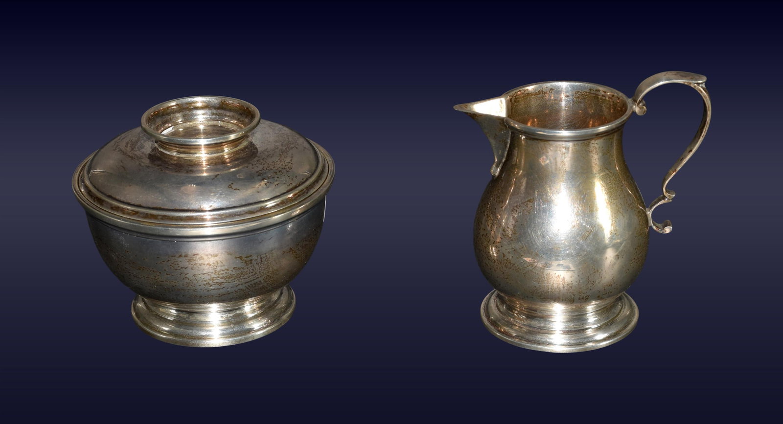 Sterling Silver Sugar and Creamer: 20th C. Ensko, New York. Both marked on bottom "Reproduction Circa 1750". Circular footed bodies, molded rims. Sugar bowl has a fitted domed cover. Creamer has a scroll handle. Creamer: 3 1/2" high x
