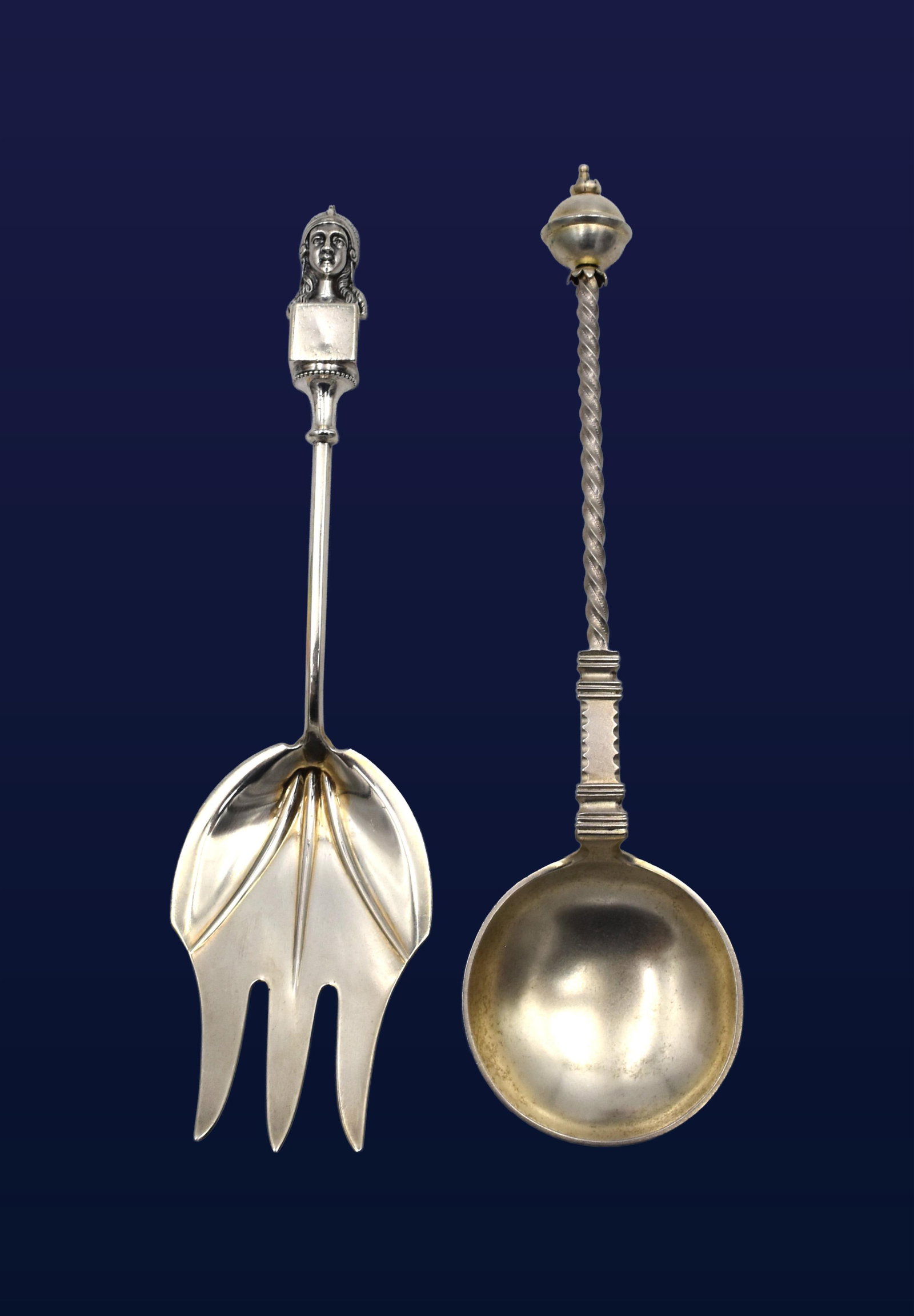 (2) Sterling Silver Serving Pieces: 19th C. To include: (A) Serving fork with an Egyptian Revival bust head. 9" long. 2.7 ozt. (B) Swedish vermeil spoon. Orb style finial, twisted shaft. 9 1/2" long. 2.22 ozt. Good condition with age