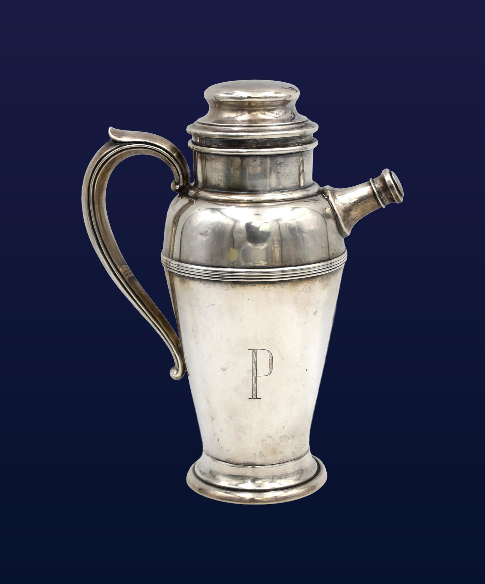 Sterling Silver Cocktail Shaker: 20th C. Loop handle, side spout and removable lid. Stamped on bottom "Fisher sterling". 10 1/4" high x 8" wide from spout to handle x 3" diameter at opening. 19.07 ozt.Shows dents. Monogrammed.