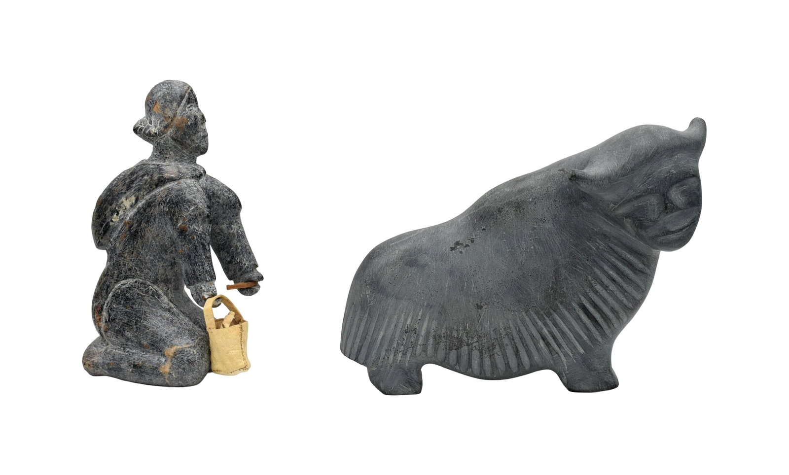 (2) Inuit Stone Carvings: 20th C. To include: (A) Musk ox. Unsigned. 6 1/2" high x 8" wide x 2 1/2" deep. (B) Kneeling woman with water buckets made from animal skin. Signed illegibly on bottom. 7" high x 3 1/2" wide x 2"