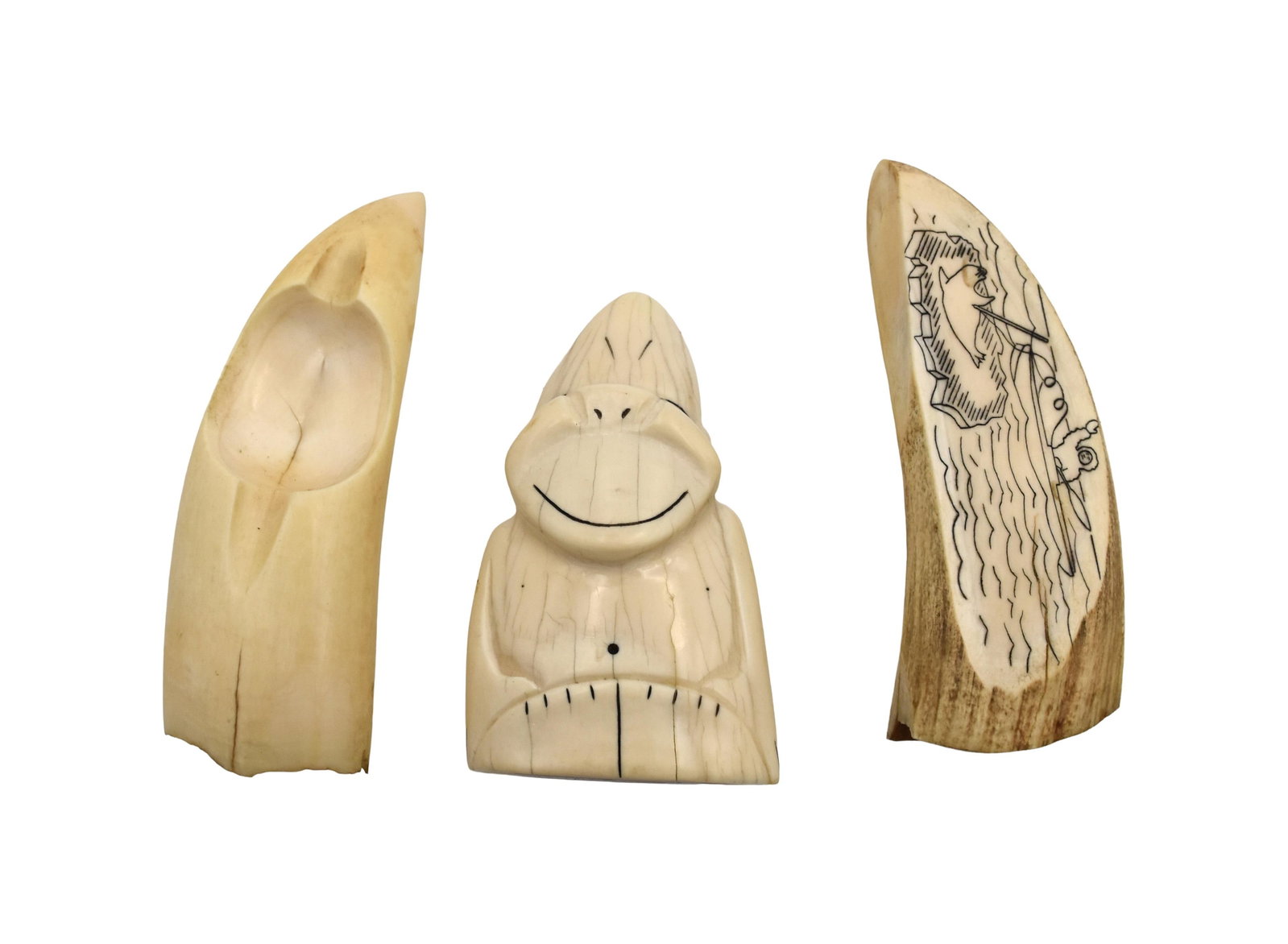 (3) Carved Sperm Whale Teeth: 20th C. To include: (A) In the form of an ashtray. 5 1/4" long x 1 3/4" wide. (B) Polished on two sides. Pacific Northwest sealing scene. Verso blank. 5 1/4" long x 2" wide. (C) Carved Billiken. 4