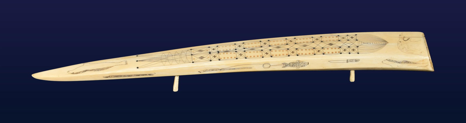 Inuit Walrus Tusk Cribbage Board: Early 20th C. Decorated with bears, seals, fish, harpoons, knives, fish hooks and cooking pot. Stands on peg legs. 2" high x 22 1/2" long x 3" wide. Good original condition. No game pegs. Shipping