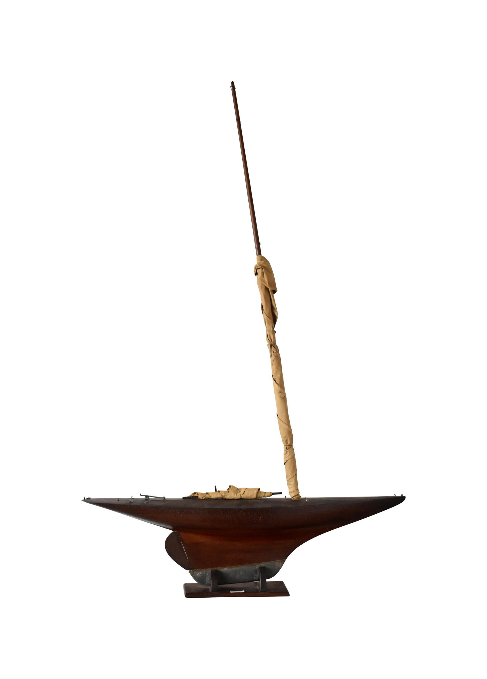 Pond Model: Late-19th/Early-20th C. Wooden plank construction. Probably mahogany. Lead keel. Old alligated finish. On a mahogany stand. Boat: 11" high x 8" wide x 41 1/2" long. Main mast: 53" high. Jib: 13"