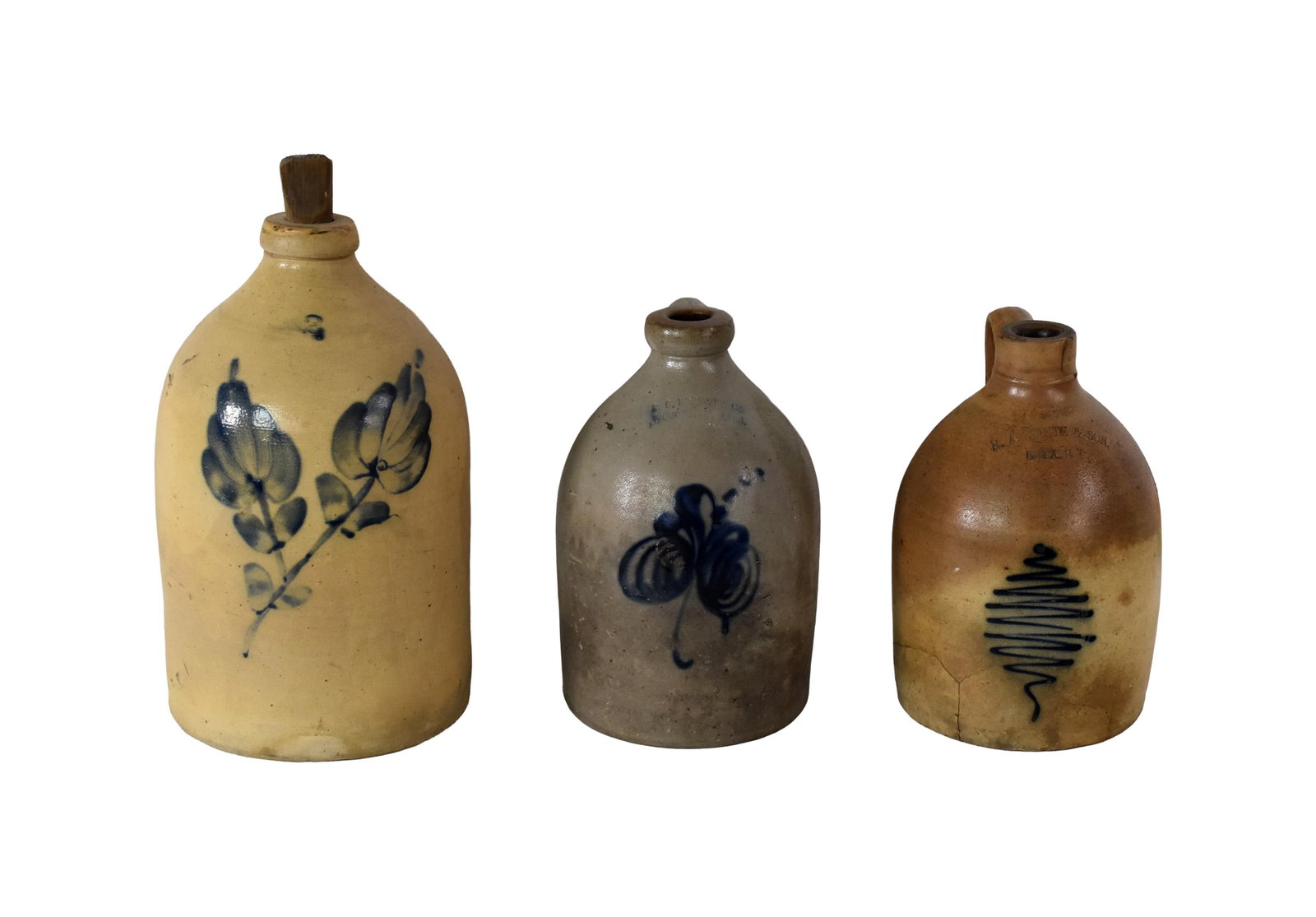 (3) Stoneware Handled Jugs: Late 19th C. To include: (A) Two gallon jug with floral decoration. 15" high x 9" wide. (B) One gallon jug by N.A. White & Son, Utica, New York. Deep blue swirl design. 12" high x 8" wide. (C) One