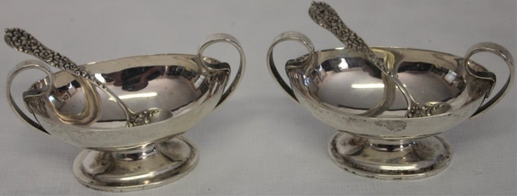 PAIR OF DAVID CARLSON FOOTED STERLING SILVER SALTS: CLASSICAL STYLE ALONG WITH TWO ORNATE STERLING SALT SPOONS WITH EMBOSSED FLORAL DESIGN, 4.8 OZT, 1 1/2" HIGH X 3 3/4" WIDE, 2" DEEP, SPOONS 3 1/8" LONG.
