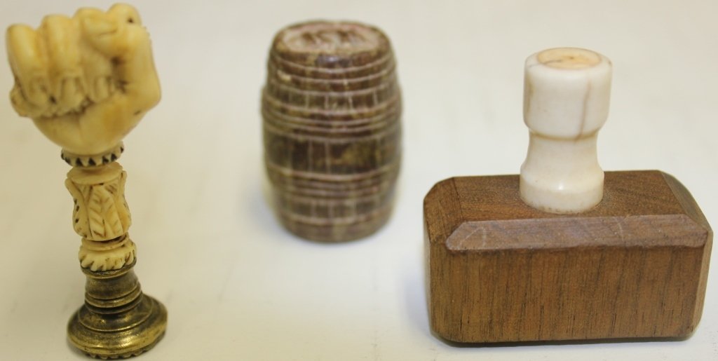 ANTIQUE WHALE IVORY ENVELOPE SEALER LATE 19TH C: WITH CARVED FIST WITH SNAKE, 2" HIGH; SOAPSTONE OIL BARREL SEAL, 1 3/8" HIGH; WOODEN COFFIN STAMP, 1 5/8" HIGH; 3 PIECES; DAVID ARMS COLLECTION