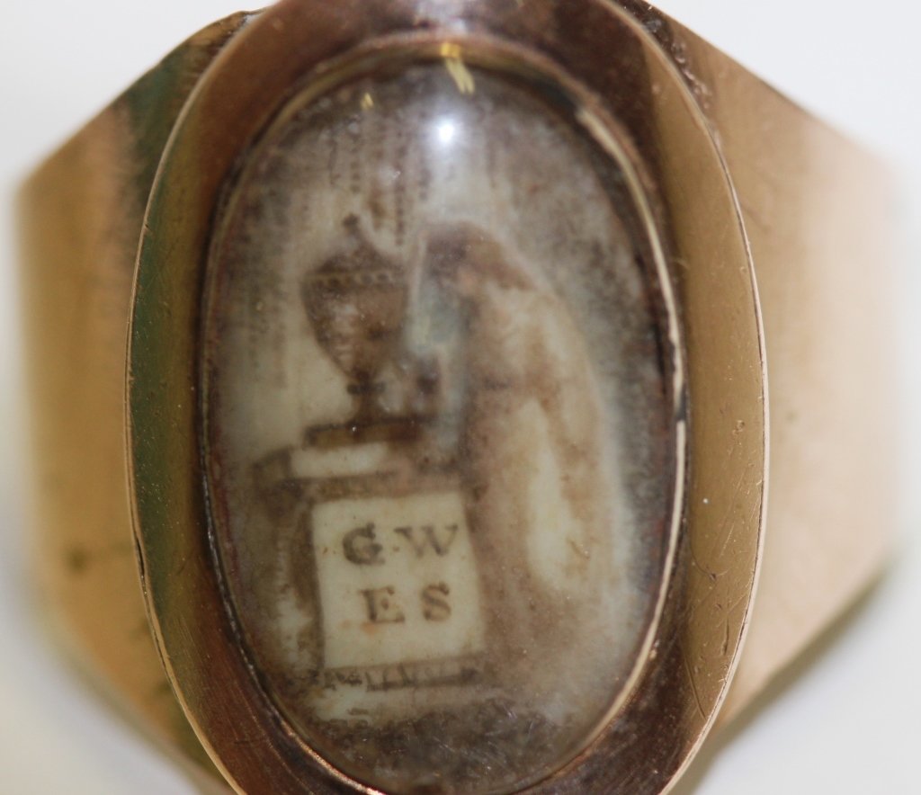 GEORGIAN MEMORIAL RING WITH SEPIA MEMORIAL: PAINTING ON IVORY OF LADY, PLINTH, URN, WEEPING WILLOW; PLINTH HAS "G W/E S" ON IT. SETTING EITHER LOW CARAT GOLD OR GOLD FILLED; OVAL TOP OF RING 7/8" X 5/8"; THERE ARE 2 SMALL CHIPS AND A SMALL SCRA