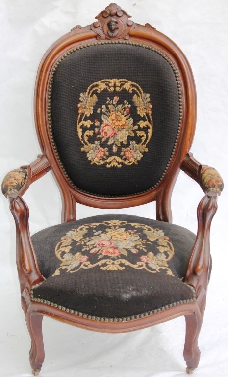 AMERICAN VICTORIAN WALNUT ARM CHAIR CA 1880: WITH CARVED JELLIFF STYLE HEAD; OLD NEEDLEPOINT UPHOLSTERY ON SEAT AND BACK; 42 1/2" HIGH, 27" WIDE, 23" DEEP