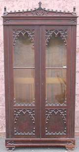 MID 19TH C AMERICAN GOTHIC BOOKCASE, MAHOGANY: WITH CARVED CREST, 2 GLASS DOORS, 6 ADJUSTABLE SHELVES, 89" H X 44" W X 14 1/2" D, OLD FINISH SHOWS SOME AREAS OF WEAR, 2 SEPARATIONS IN FRETWORK.