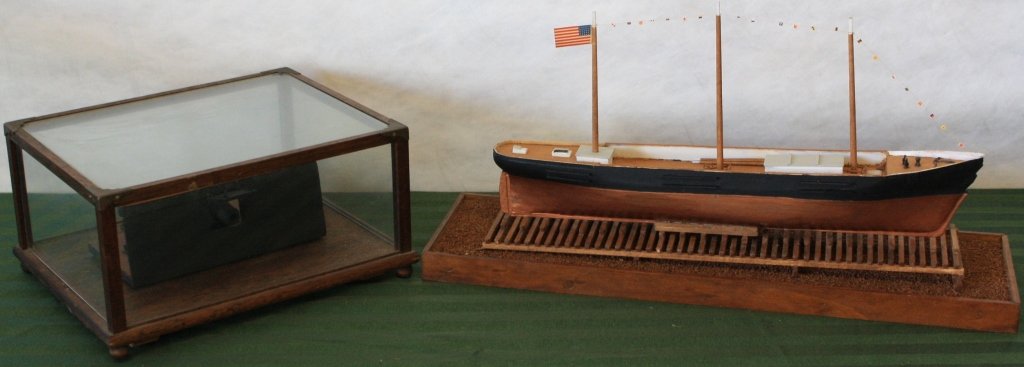 2 HANDMADE 20TH C WOODEN MODELS TO INCLUDE: THE WHALESHIP KAPE CORY IN DRY DOCK. 11" HIGH X 19" LONG. ALONG WITH A MODEL GUN PLACEMENT WITH CANNON IN CASE. 6" HIGH, 12" WIDE, 9 1/2" DEEP.
