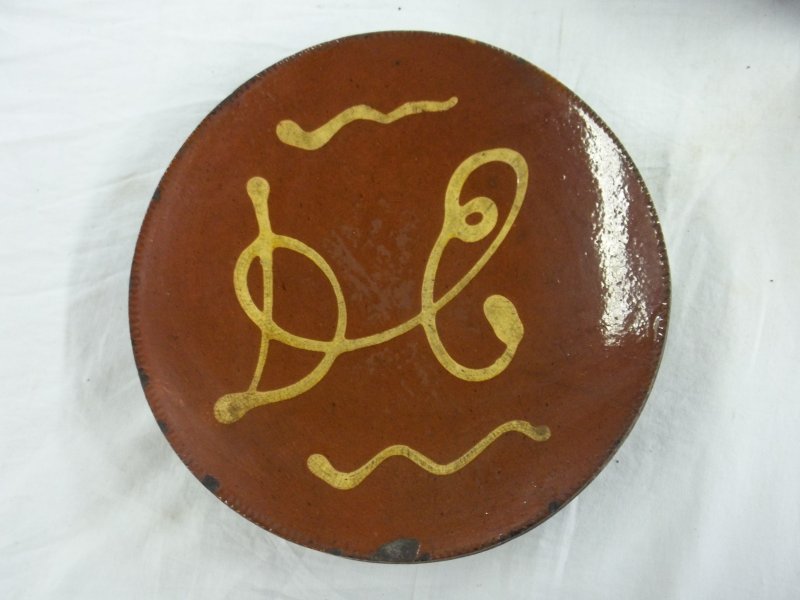 Redware plate with yellow slip decoration: Redware plate with yellow slip decoration, DE with squiggles, 9 1/4" diameter -- old chip on edge