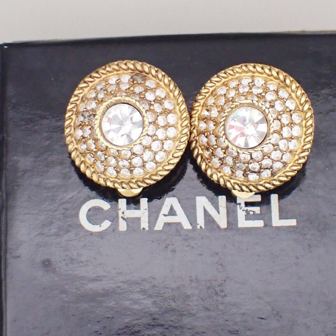 CHANEL Logo Rhinestone Round Button Earrings: CHANEL Logo Rhinestone Round Button Earrings Clip-On Gold-Plated France 63YF791 Condition: Pre-owned Seller Notes: ?One of rhinestone is missing.Please check a photograph and the text carefully.? Shap