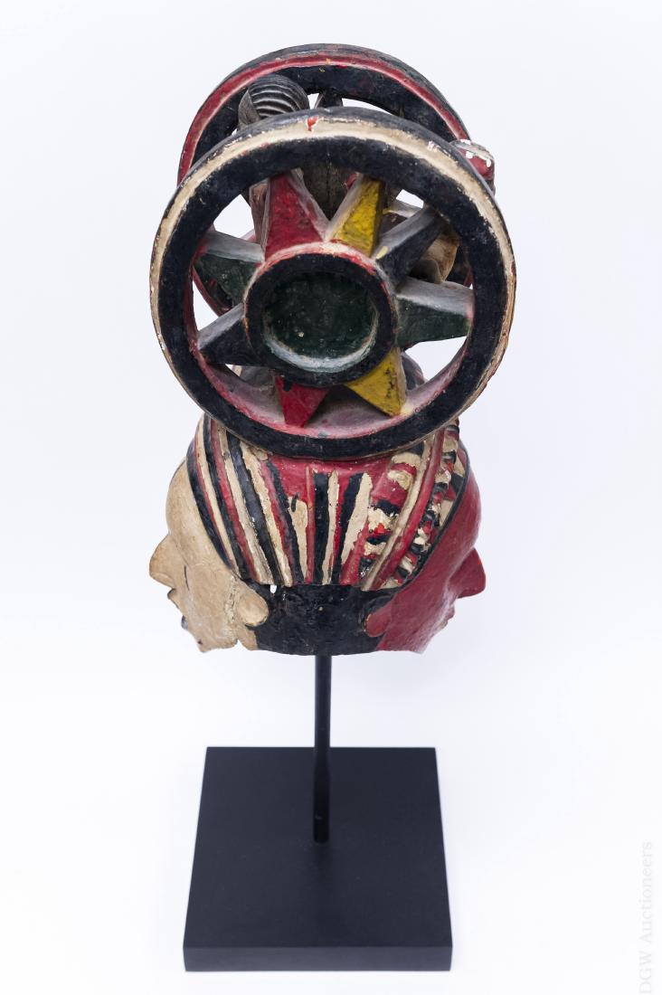 Polychrome Double Mask Sculpture on Stand.: Polychrome double mask sculpture on stand. Hand painted double sided mask with 2 wheels and 2 figures on top. On a wood stand with pole. (Overall: 32" tall).