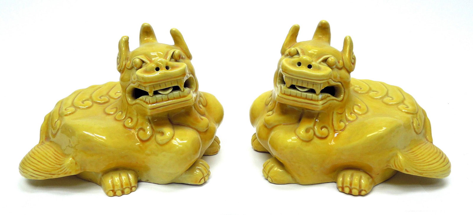 Pair of Chinese Pottery Foo Dogs.: Pair of Chinese yellow glaze pottery figures of opposing crouching Foo dogs bearing teeth. 6 x 9 inches.
