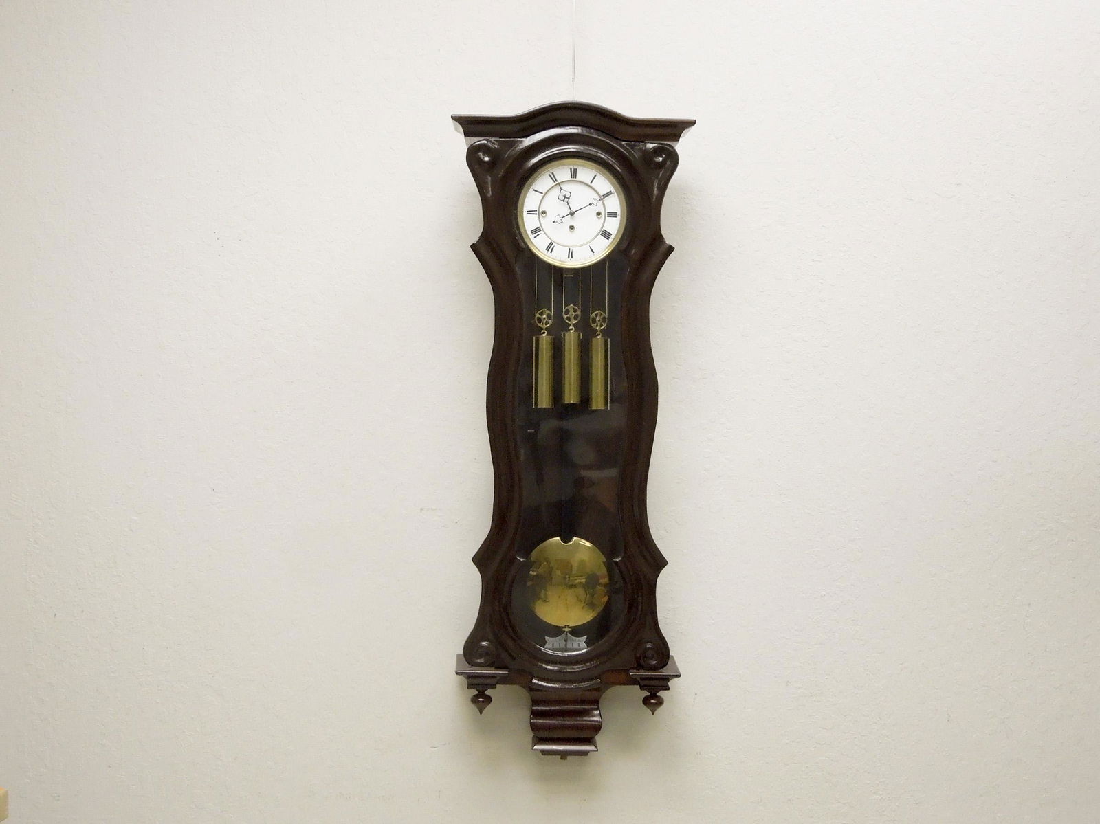 Vienna Regulator Wall Clock.: Vienna regulator wall clock. Mahogany case with a dark finish. Circular face with time and strike. Three weighted, grande sonnerie, pendulum movement. With later finial and bottom ornament. 49" x 17".
