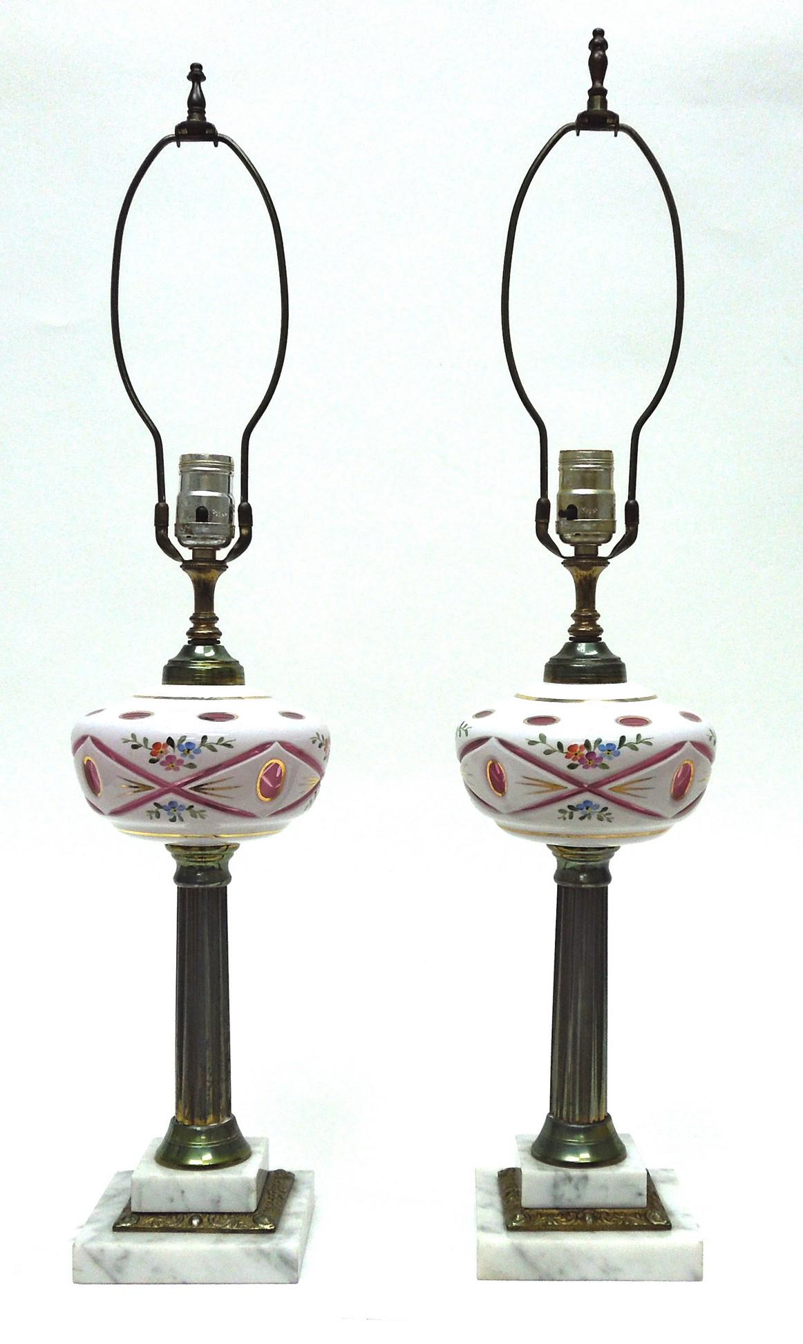 Pair of Bohemian cased glass table lamps.: Pair of Bohemian table lamps. White cased glass front bases, cut to ruby glass with enameled floral sprays, on metal columns with stepped white marble plinths. White silk shades. Mid 20th C. (27 inche
