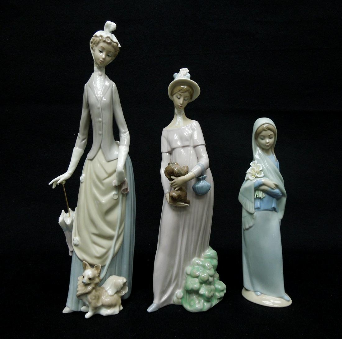 (3) Lladro Porcelain Figures.: (3) Lladro porcelain figures. Lady with umbrella and dog, Lady with dog and girl with lilies. 13 3/4", 11 1/2", 9 1/4" tall.