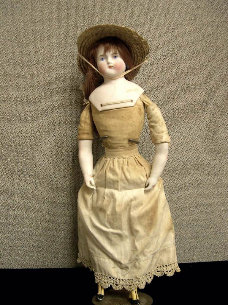 Circa 1900 Biedermeier style bisque doll: Biedermeier style doll, bisque domed shoulder head, painted facial features, pierced ears. Human hair wig, bisque arms and legs, original cloth body. Wearing a straw hat, antique under-slip, bloomer
