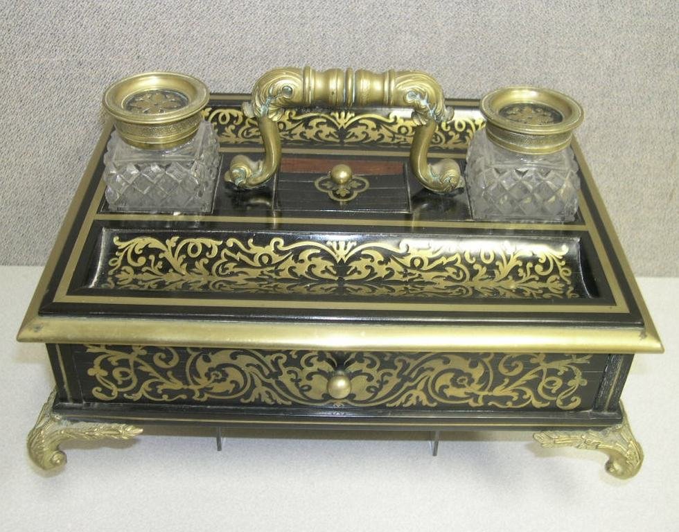 Regency boulle work Ink Stand: Regency ebonized wood and gilt-bronze boulle work inkstand. The rectangular top with gilt bronze handle centering two cut glass inkwells with conforming boulle work lids, a lidded compartment and a pa