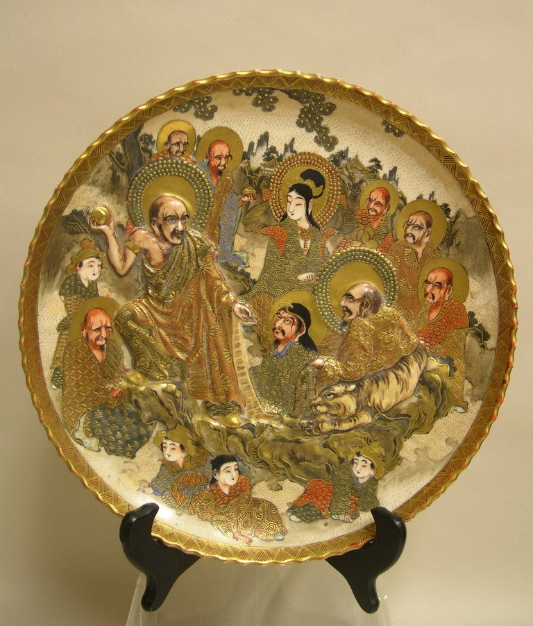 Japanese Satsuma Ware Plate Buddhist Arhats: Japanese Satsuma pottery Plate with Buddhist Arhats and personages in a landscape. Signed in gold on a red enamel rectangle. Diameter: 10 inches