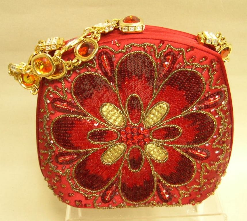 Judith Leiber Red Silk Evening Bag Sequins Rhinestones: Judith Leiber red silk evening bag having a single amber and white rhinestone clasp set in gold metal hardware and matching double chain. Bag is decorated on two sides with an eight petal sequin and b