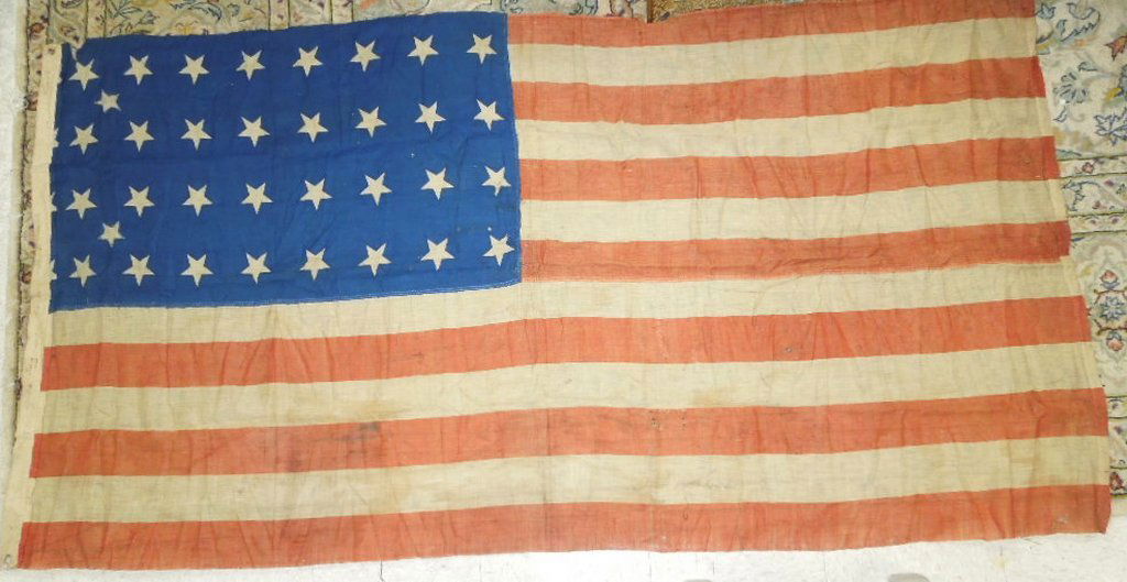 1862 US Old Glory Flag: 1862 US Old Glory flag. Hand stitched in two sections of red and white stripe cloth with blue and 36 white star inset. Two additional stars appliqued within. "Tobias 1862" inscribed on the canvas selv