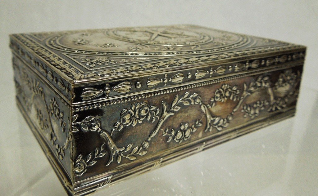 German 800 Silver Repousse Box: German 800 silver box with hinged lid. Repousse foliate and garland decoration overall, with torch and quiver of arrows trophy medallion decorated top. Crescent and crown mark on obverse. Stamped 800.