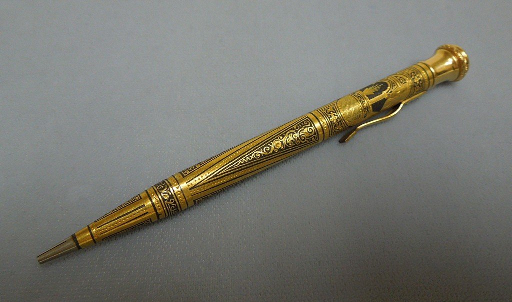 Gold and Niello Propelling Pencil: Arabesque gold and neillo propelling pencil.Calligraphic inscription at lower circumference. Early 20th Century. Tests 10Kt. Length: 4 3/4 inches.