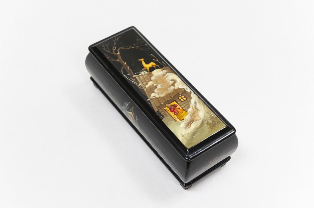 Russian Lacquer Box: Russian footed rectangular black ground lacquer box with gold border detailing and red interior. Miniature painting of a girl looking up at a golden deer on the roof. Vignettes of a deer on the roof o