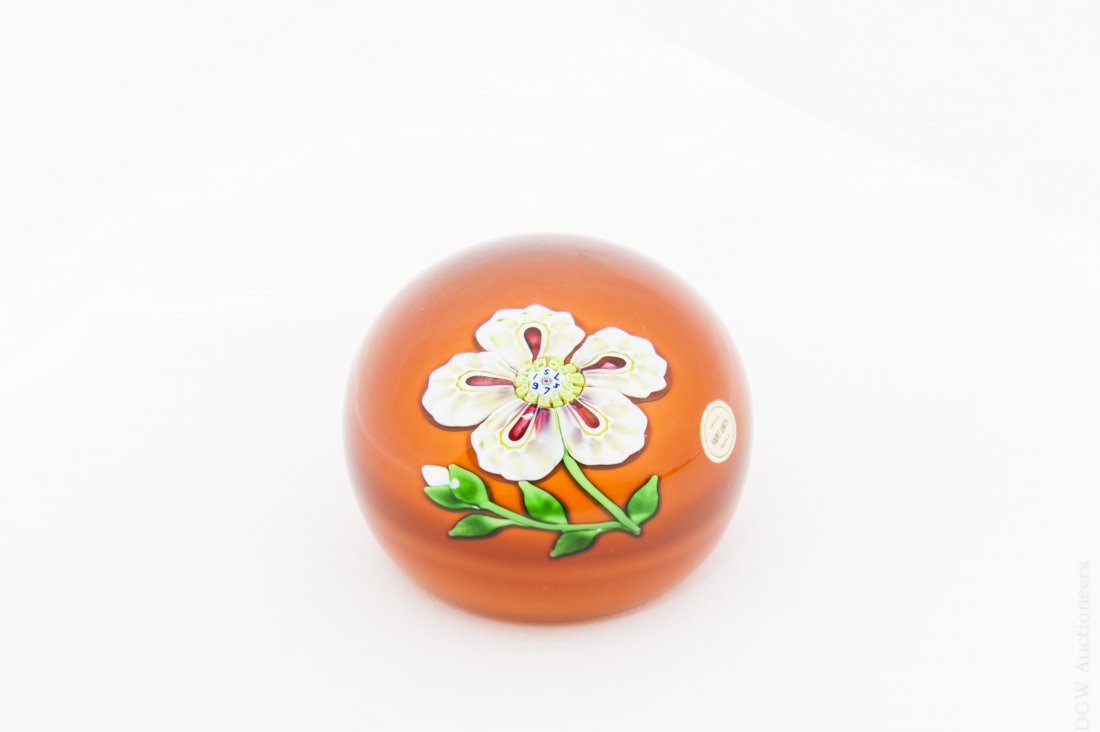 Saint -Louis Art Glass Paperweight.: Saint- Louis art glass paperweight. Orange base with a white flower and bud in center. Marked SL 1973. ( Approx. 2 ½" x 2 ½"). From the collection of Eric Sinizer.
