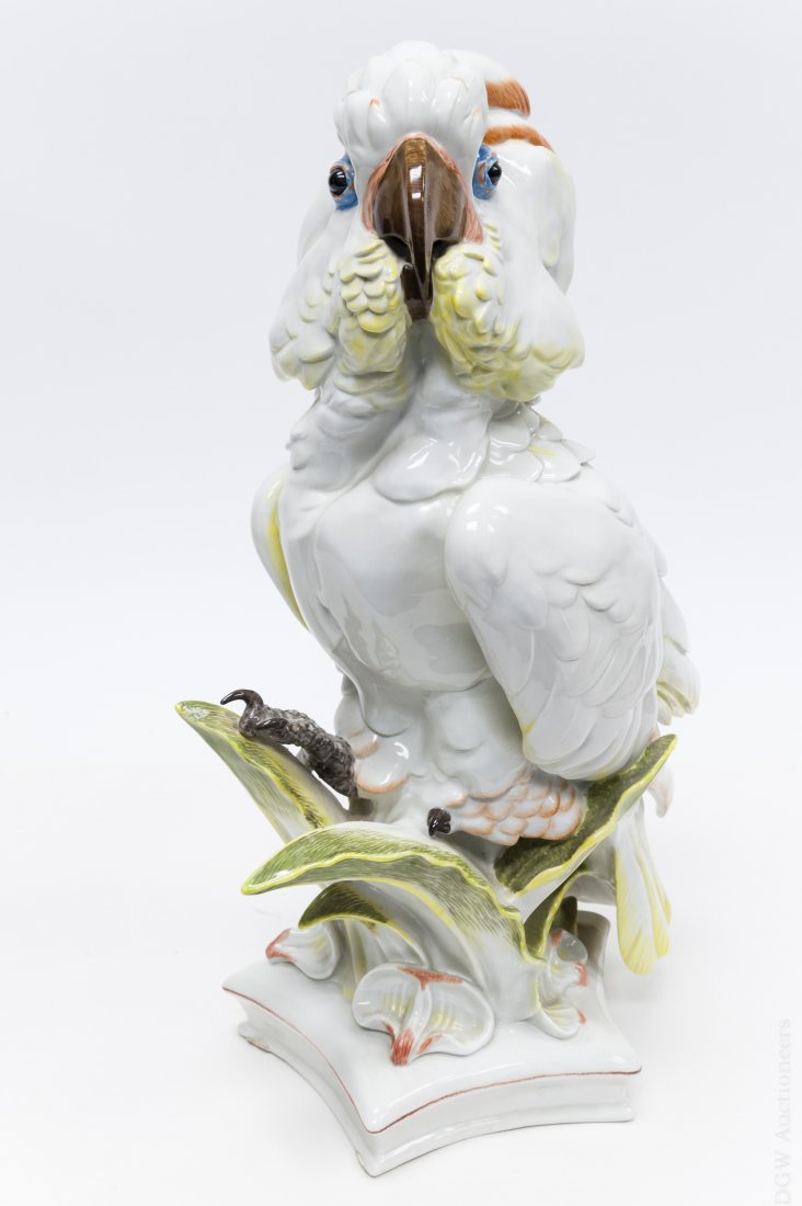 Meissen Porcelain Cockatoo.: Meissen porcelain cockatoo perched on leaf fronds on a pentagonal base. Blue under glaze cross sword mark on rim of base. Incised on base: 146B, 14295. Height: 18 inches.