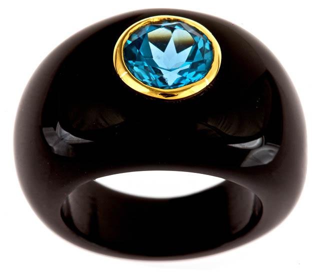 BLACK ONYX AND SWISS BLUE TOPAZ RING: Band Crafted Of Smooth Black Onyx. With A Highly Polished Finish, A Shimmering Swiss Blue Topaz Sits In A Luminous Goldtone Bezel Setting On This Pretty Ring. Gemstone Colors: Blue Gemstone Shapes: Ov